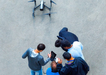 Students gathered around a drone control unit drone on the ground below them