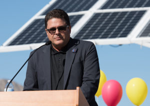 regional director jon caffery at a podium in front of huge solar panels