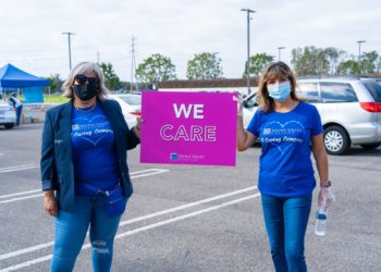 two IVC staff members holding We Care sign